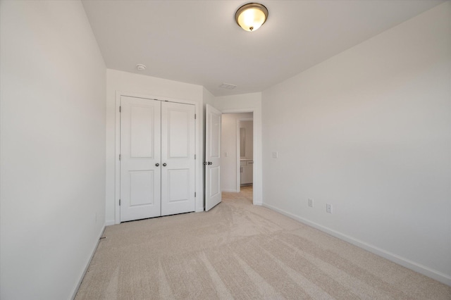 unfurnished bedroom featuring baseboards, a closet, and light colored carpet