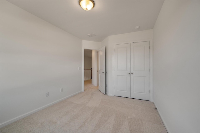 unfurnished bedroom featuring a closet, light carpet, and baseboards