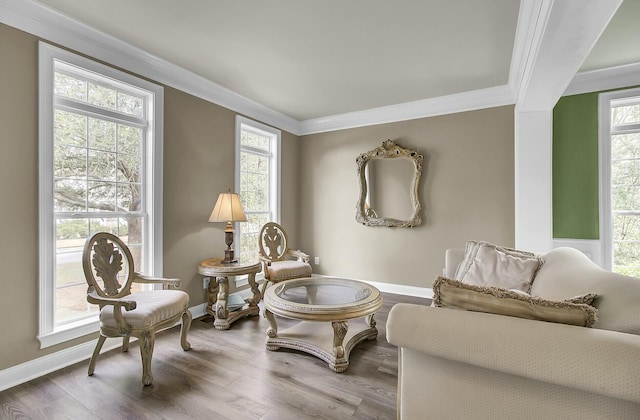 living area with baseboards, a healthy amount of sunlight, wood finished floors, and crown molding