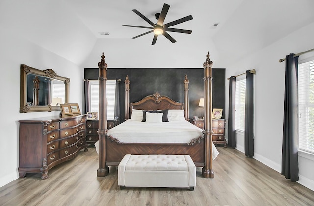 bedroom featuring ceiling fan, wood finished floors, visible vents, baseboards, and vaulted ceiling