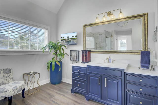 full bathroom with baseboards, wood finished floors, vaulted ceiling, vanity, and a shower stall