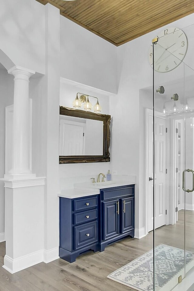 bathroom featuring a stall shower, vanity, wood finished floors, wooden ceiling, and ornate columns