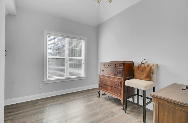 living area featuring vaulted ceiling, wood finished floors, and baseboards