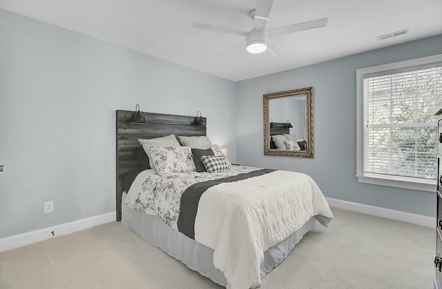 bedroom featuring baseboards, visible vents, a ceiling fan, and light colored carpet