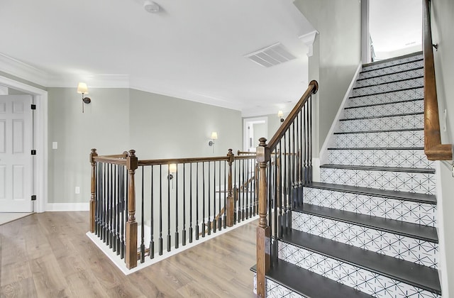 stairs with baseboards, visible vents, wood finished floors, and ornamental molding