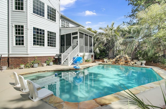 pool with a sunroom, a patio area, and grilling area