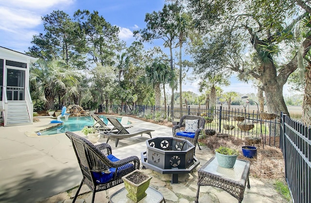 view of patio / terrace with a fenced in pool, an outdoor fire pit, a sunroom, and a fenced backyard