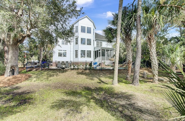 rear view of house featuring a sunroom, fence, and a yard