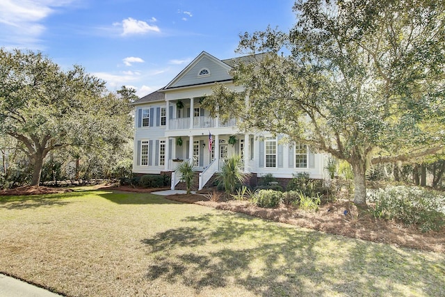 neoclassical / greek revival house featuring covered porch, a front lawn, and a balcony