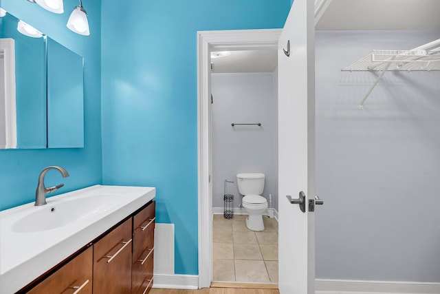 bathroom with baseboards, vanity, toilet, and tile patterned floors