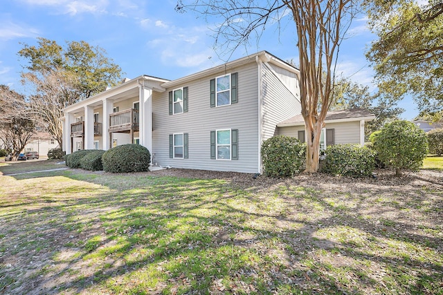 view of front of property featuring a front yard and a balcony