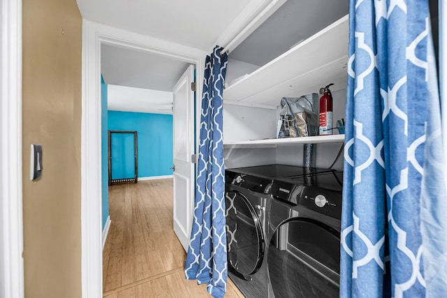 laundry area with wood finished floors, laundry area, baseboards, and separate washer and dryer