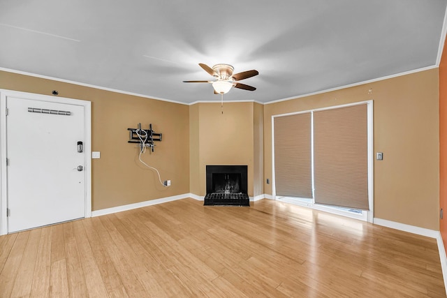 unfurnished living room with baseboards, a fireplace with raised hearth, ceiling fan, light wood-style flooring, and ornamental molding