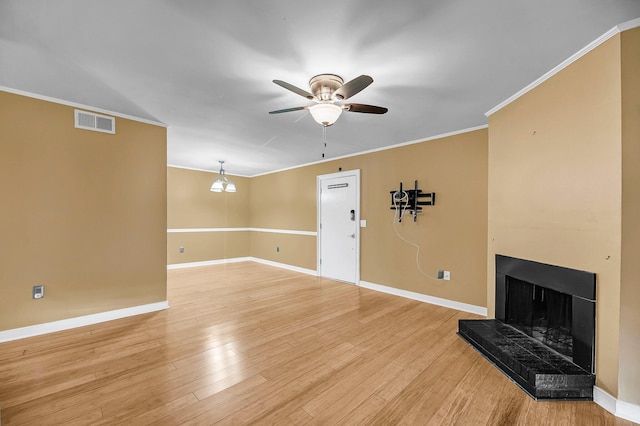 unfurnished living room featuring crown molding, visible vents, a fireplace with raised hearth, light wood-type flooring, and baseboards