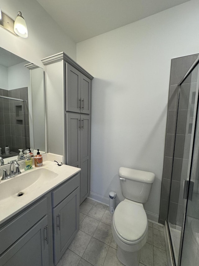 bathroom featuring toilet, vanity, baseboards, a shower stall, and tile patterned floors