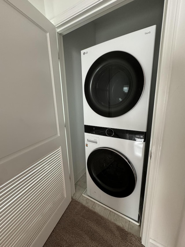 laundry room with stacked washing maching and dryer, laundry area, and tile patterned floors