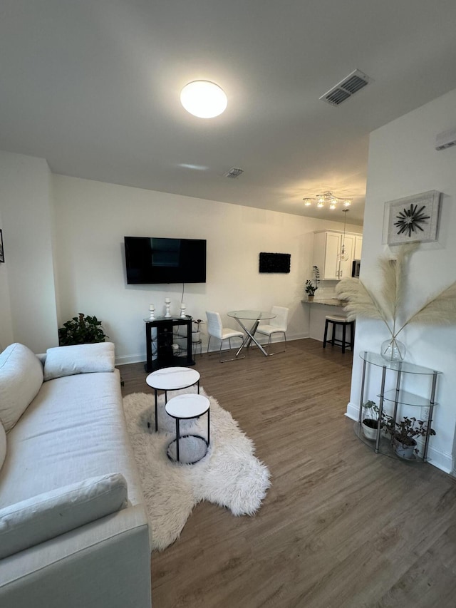 living area with visible vents, baseboards, and wood finished floors