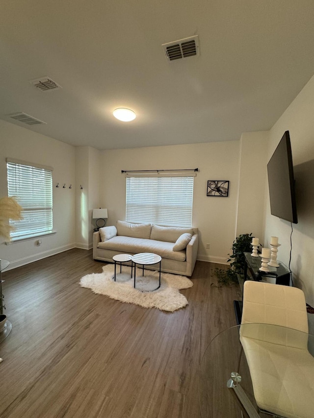 living room featuring plenty of natural light, visible vents, and wood finished floors