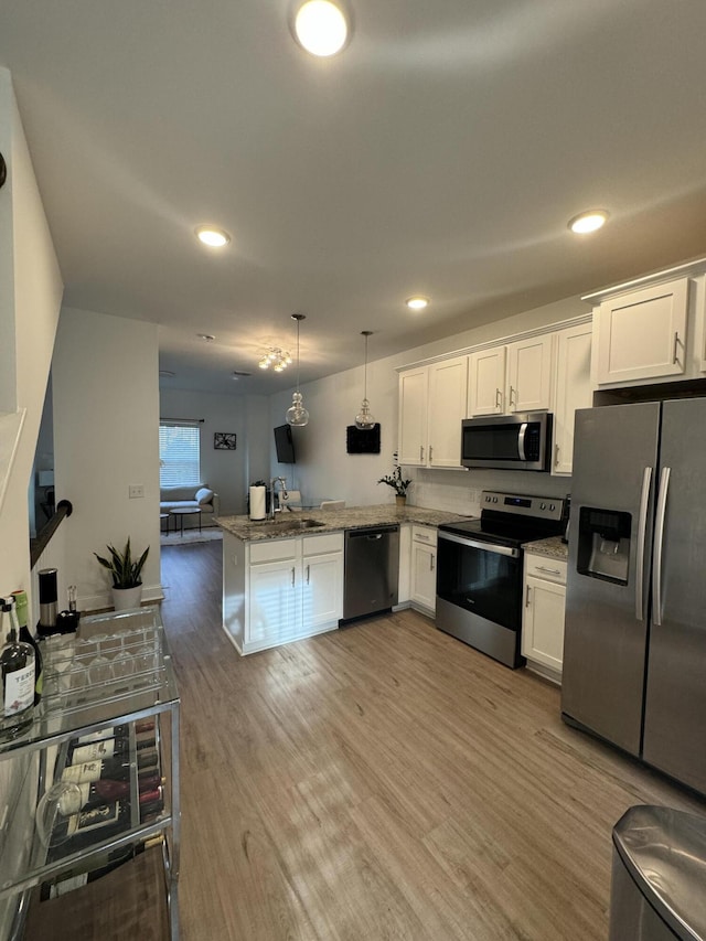 kitchen with a peninsula, light wood-style floors, open floor plan, white cabinets, and appliances with stainless steel finishes