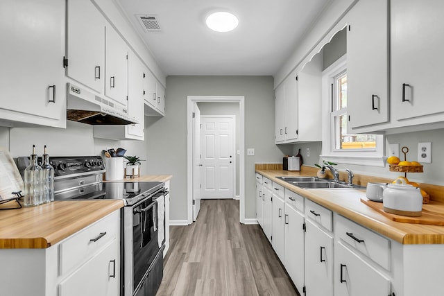 kitchen featuring under cabinet range hood, white cabinetry, a sink, and stainless steel range with electric cooktop