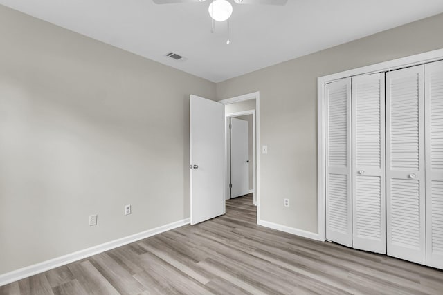 unfurnished bedroom featuring light wood-type flooring, visible vents, baseboards, and a closet