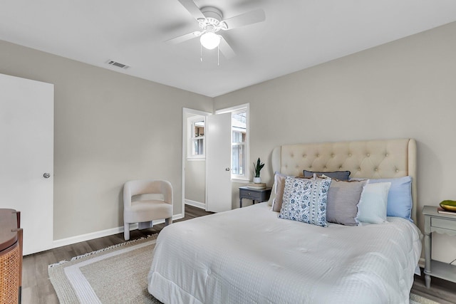 bedroom with visible vents, baseboards, wood finished floors, and a ceiling fan