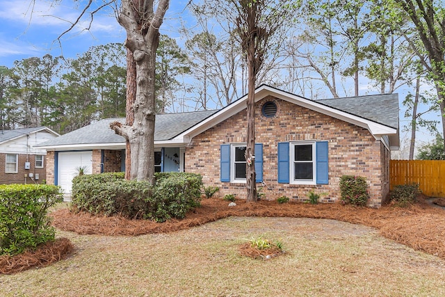 ranch-style home with an attached garage, fence, brick siding, and a shingled roof