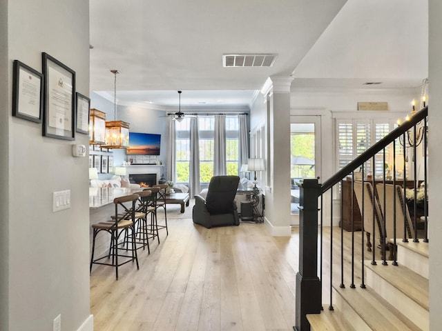 interior space with visible vents, stairway, crown molding, and a ceiling fan