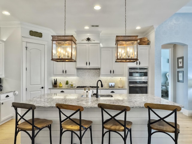 kitchen with visible vents, a sink, backsplash, stainless steel appliances, and crown molding