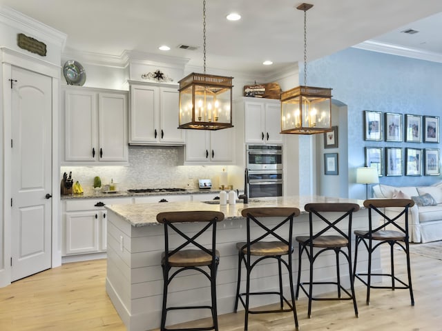 kitchen with visible vents, a kitchen bar, a notable chandelier, appliances with stainless steel finishes, and crown molding