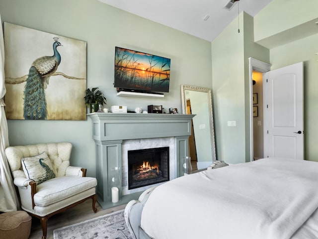 bedroom featuring wood finished floors, visible vents, and a high end fireplace