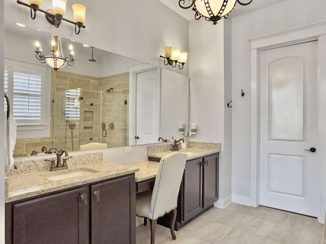 bathroom featuring vanity, baseboards, a stall shower, and a chandelier