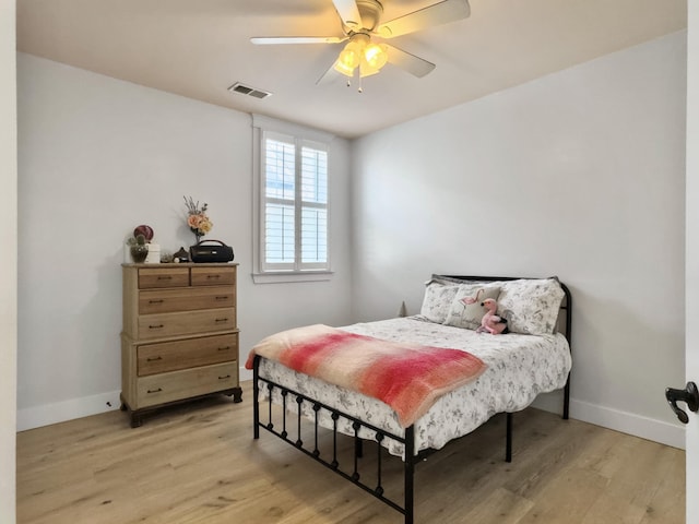 bedroom featuring light wood-type flooring, visible vents, baseboards, and ceiling fan