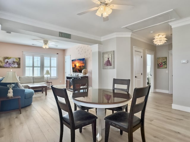 dining space with attic access, crown molding, a ceiling fan, and light wood finished floors