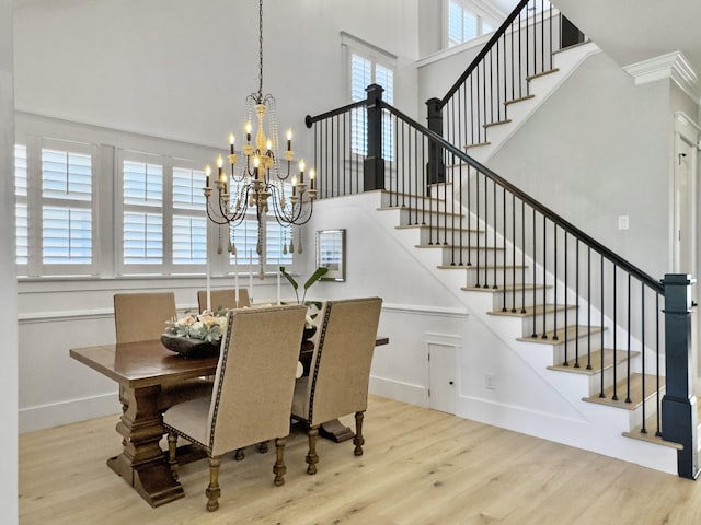 dining area featuring stairway, a notable chandelier, wood finished floors, and a high ceiling