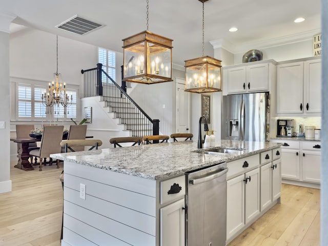 kitchen featuring visible vents, ornamental molding, a notable chandelier, stainless steel appliances, and a sink