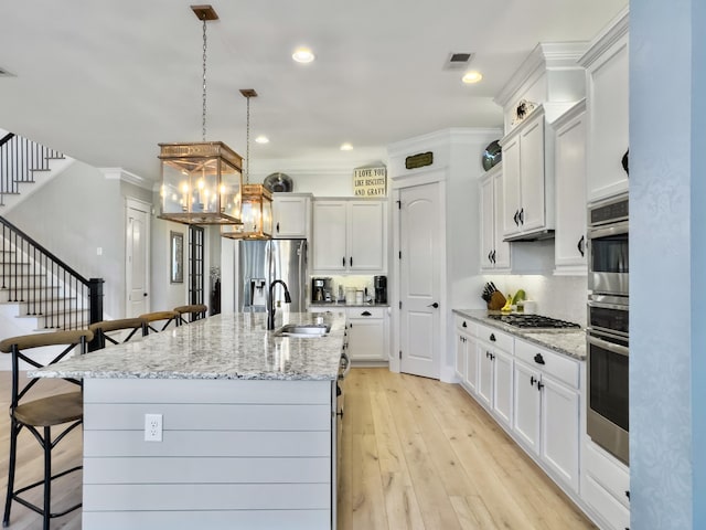 kitchen featuring visible vents, light wood-type flooring, a kitchen bar, appliances with stainless steel finishes, and an inviting chandelier