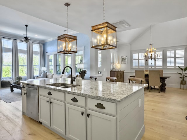 kitchen featuring a center island with sink, a sink, stainless steel dishwasher, open floor plan, and a chandelier