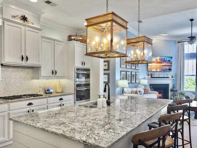 kitchen featuring visible vents, appliances with stainless steel finishes, crown molding, and a sink