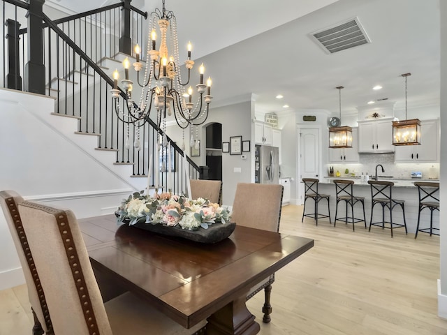 dining space with a notable chandelier, light wood-style flooring, stairway, and visible vents