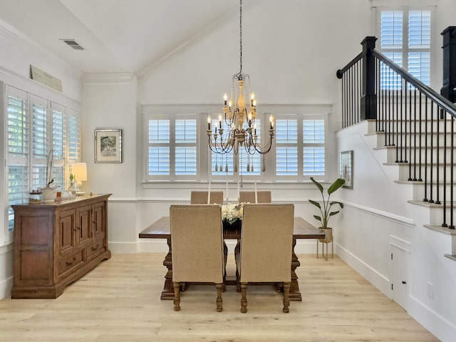 dining space with stairway, ornamental molding, vaulted ceiling, light wood-style floors, and a notable chandelier