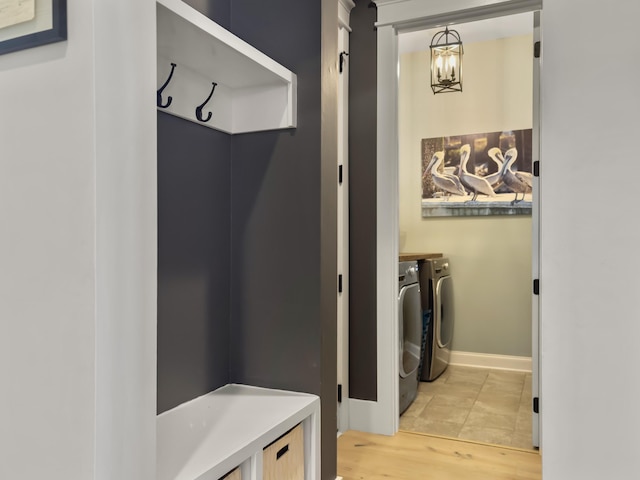 clothes washing area with laundry area, separate washer and dryer, baseboards, and light wood finished floors