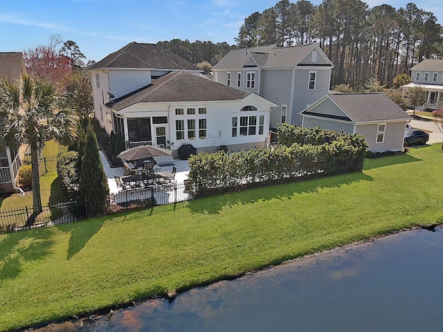 rear view of property featuring a yard, a patio, a fenced backyard, and a water view