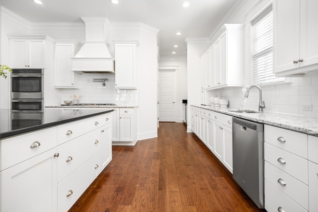 kitchen featuring white cabinetry, sink, dark stone countertops, custom exhaust hood, and stainless steel appliances