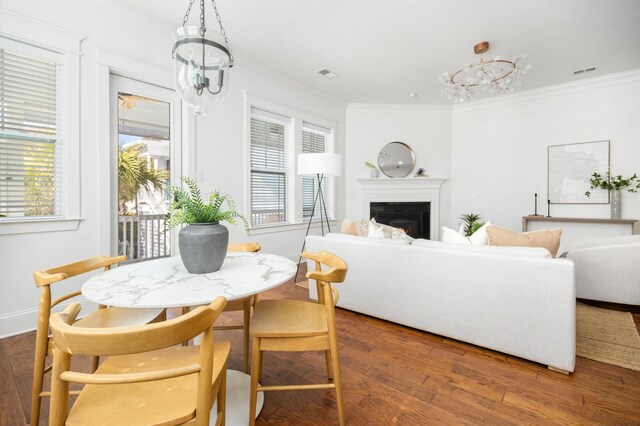 dining space with an inviting chandelier, ornamental molding, a healthy amount of sunlight, and dark wood-type flooring