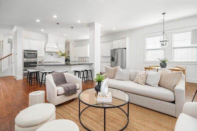 living room featuring ornamental molding, hardwood / wood-style floors, and ornate columns