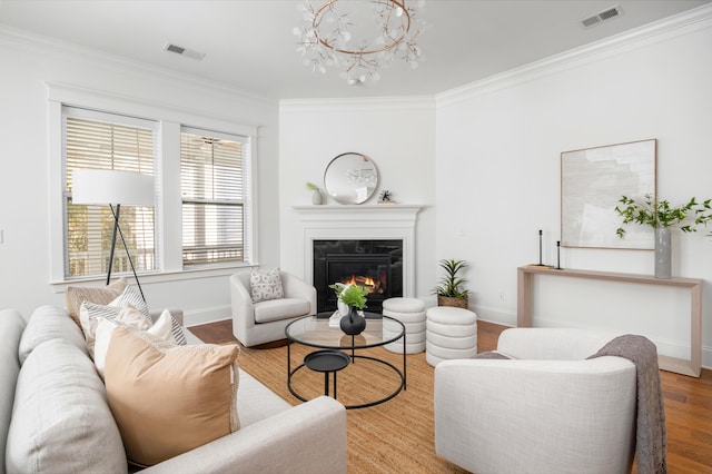 living room featuring wood-type flooring, ornamental molding, and a chandelier