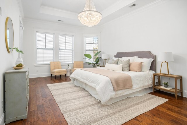 bedroom featuring crown molding, a tray ceiling, dark hardwood / wood-style flooring, and a chandelier