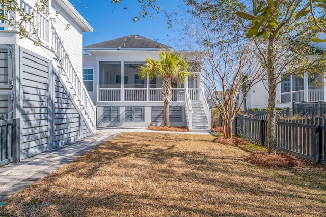 rear view of property featuring a yard and a sunroom