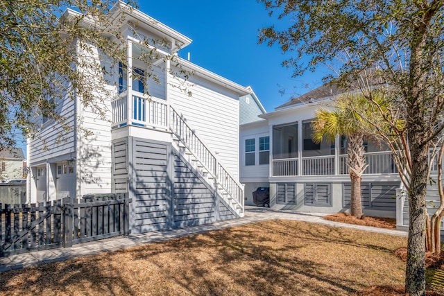 back of property featuring a garage, a sunroom, and a lawn